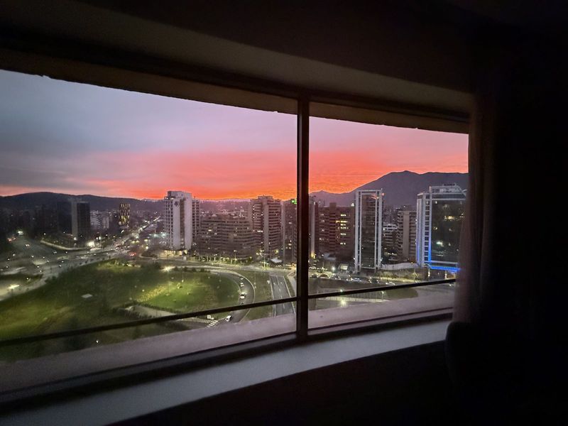 Orange sunset over Santiago and the Andes foothills, seen through a hotel window